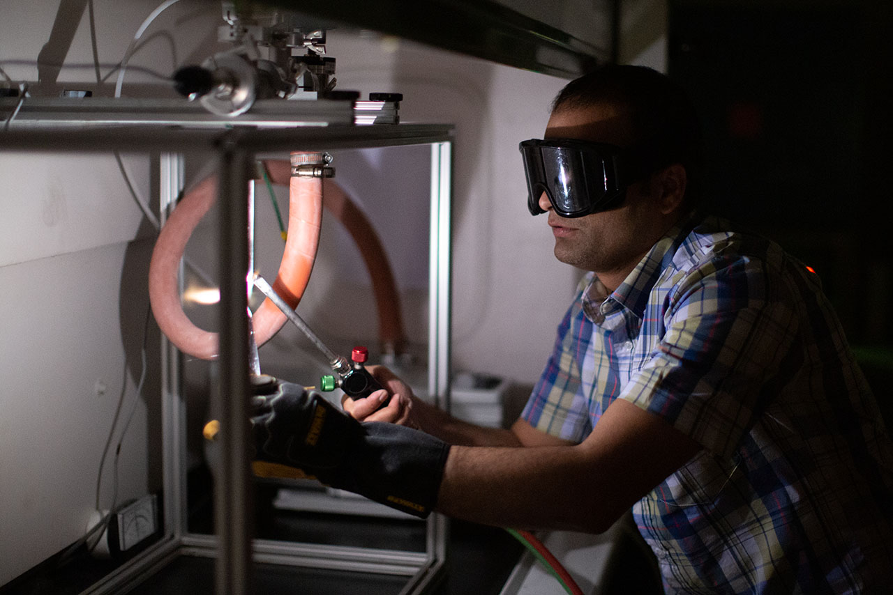 A man uses a blowtorch-like device on equipment at the Institute for Advanced Materials and Manufacturing.